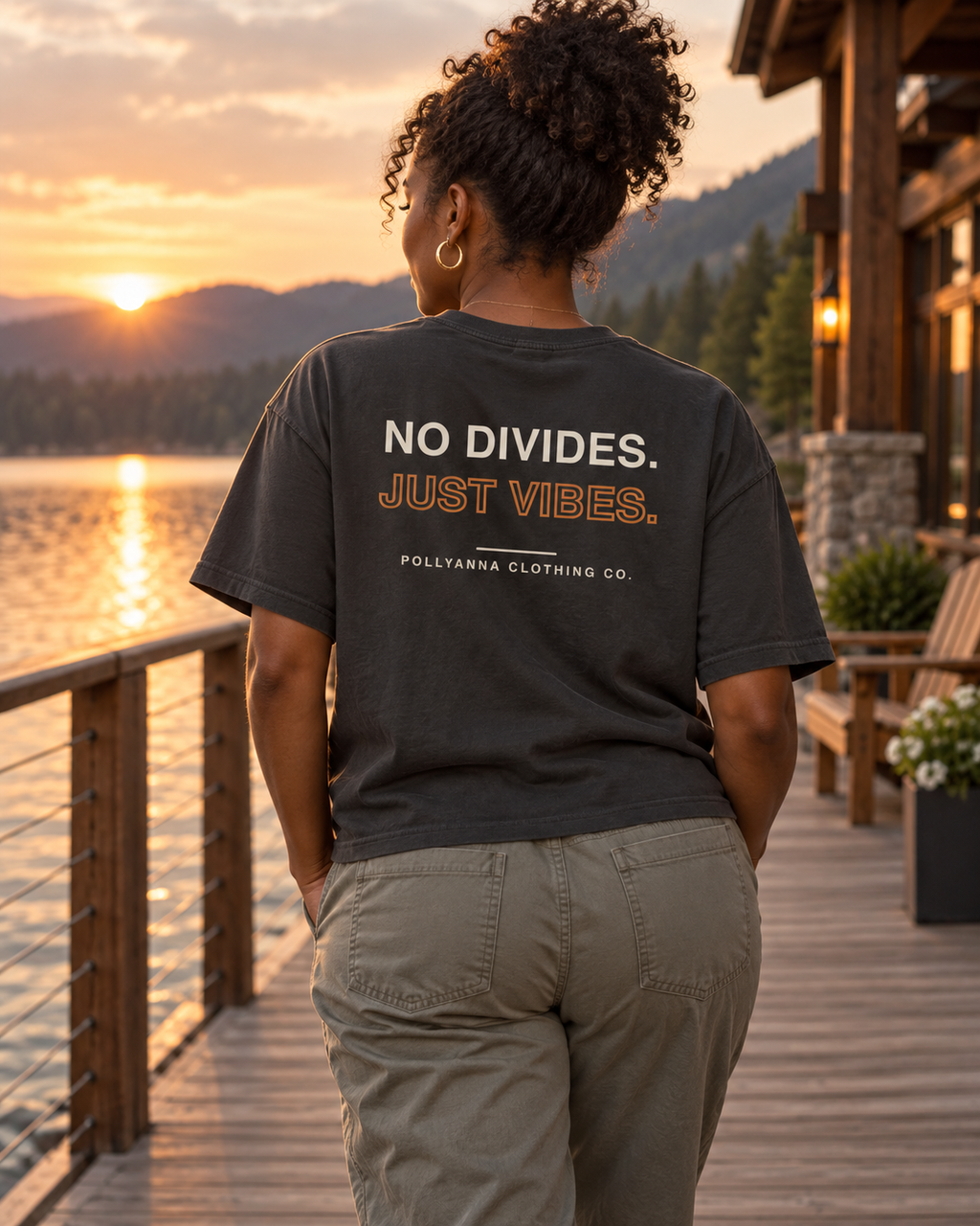 Woman wearing Heavy Faded Just Vibes tee, back view at a lakeside lodge